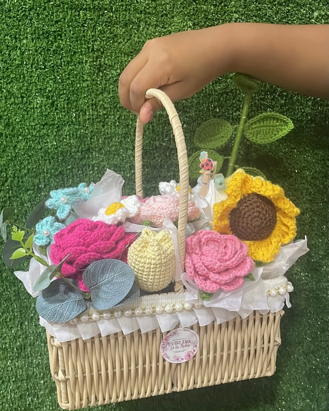 Manos tejiendo flores a crochet con hilo color rosa
